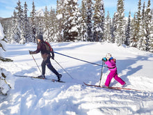 Adult towing child on cross country skis with the blue Winter / All Season TowWhee